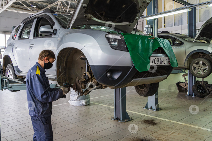 Скачать Автосалон Renault в Адыгее. Слесарь работает в защитной маске. Техническое обслуживание автомобиля Renault Duster. Карантин. Коронавирус (Covid-19). Пандемия. фотосток Ozero