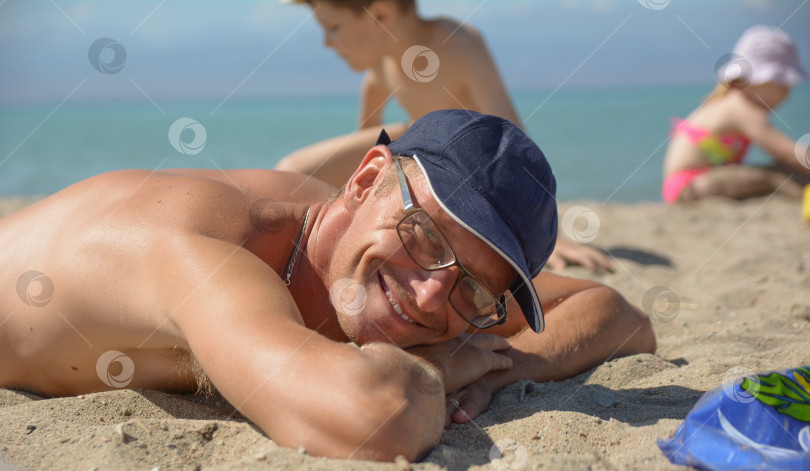 Скачать парень лежит на пляже и загорает фотосток Ozero