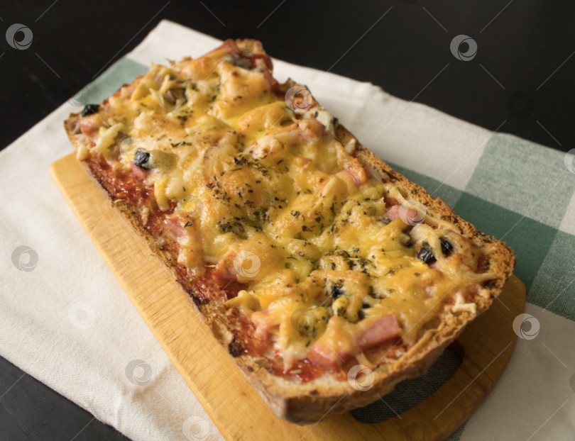Скачать Домашняя свежеприготовленная брускетта / пицца с колбасой, помидорами, оливками, сыром и приправами на старой деревянной доске на хлопчатобумажном полотенце. Простая и вкусная еда фотосток Ozero