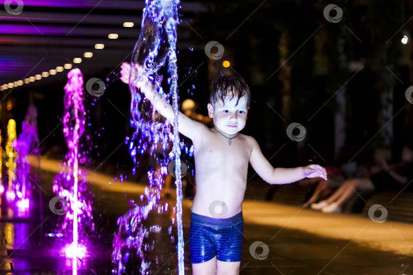 Скачать Ребенок резвится в фонтане в парке, он очень счастлив. Веселитесь и наслаждайтесь летним вечером. Прогулки и отдых. Портрет счастливого ребенка. фотосток Ozero