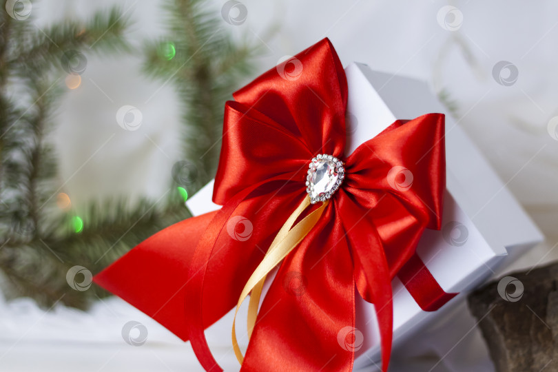 Скачать Рождественский подарок, украшенный красивым бантом на светлом фоне с еловой веточкой. Подарки, радость, сюрприз. Избирательный фокус. концепция Рождества и Нового года. фотосток Ozero