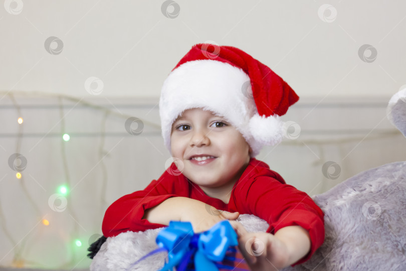 Скачать Портрет симпатичного мальчика в шапке Санта-Клауса. Забавный улыбающийся ребенок. фотосток Ozero
