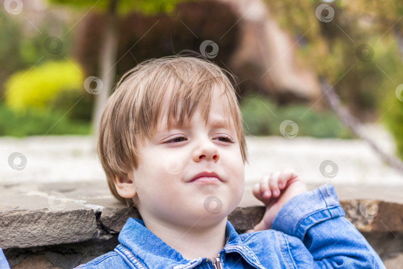 Скачать Портрет маленького ребенка крупным планом, улыбающегося на открытом воздухе на зеленом фоне. фотосток Ozero