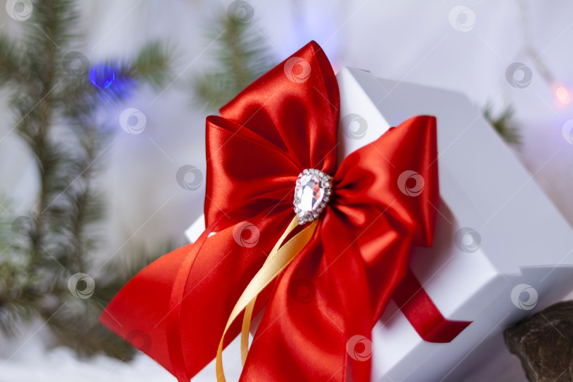 Скачать Рождественский подарок, украшенный красивым бантом на светлом фоне с еловой веточкой. Подарки, радость, сюрприз. Избирательный фокус. концепция Рождества и Нового года. фотосток Ozero