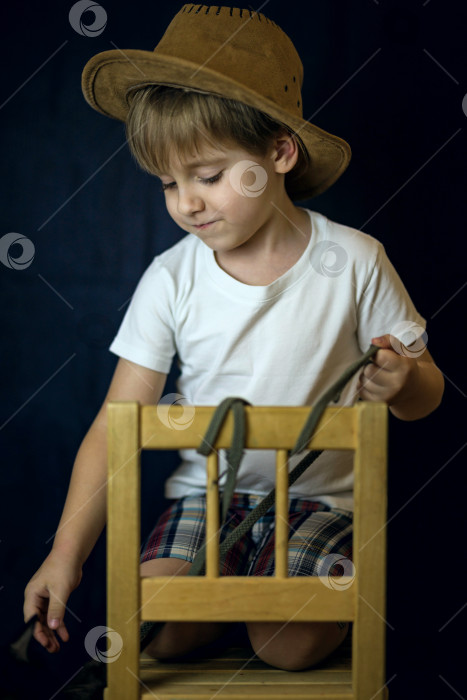 Скачать Лаконичный портрет европейского мальчика. Портрет на темном фоне мальчика в ковбойской шляпе и белой футболке. фотосток Ozero