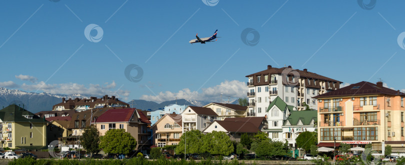 Скачать Boeing 737-8MC(WL) совершает посадку в современных жилых зданиях на побережье горной реки Мзымта на фоне вершин Кавказских гор недалеко от Сочи. Федеральная территория Сириус в Имеретинской низменности. Адлер Сириус, Россия - 19 мая 2021 г. фотосток Ozero