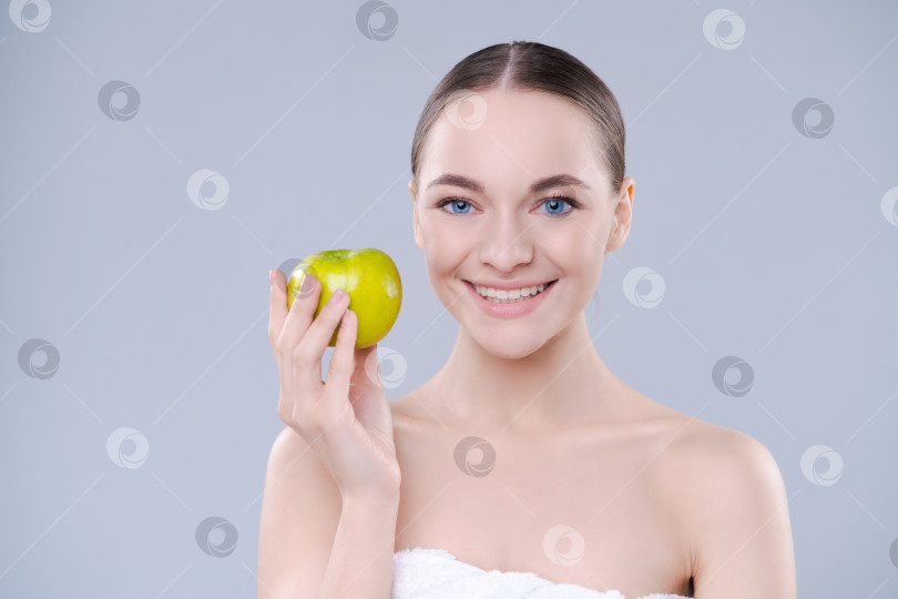 Скачать Улыбающаяся женщина с яблоком в руках на светлом фоне. студии с обнаженными плечами. фотосток Ozero