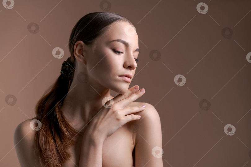 Скачать Молодая женщина с идеальной здоровой гладкой кожей касается рукой своей шеи. Модный портрет красивой женщины с легким макияжем. фотосток Ozero