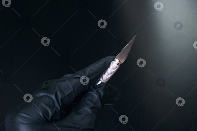 Скачать Скальпель в руке в перчатке, выделенный на черном фоне фотосток Ozero