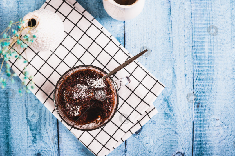 Скачать Шоколадный кекс с сахарной пудрой в кружке на столе вид сверху фотосток Ozero