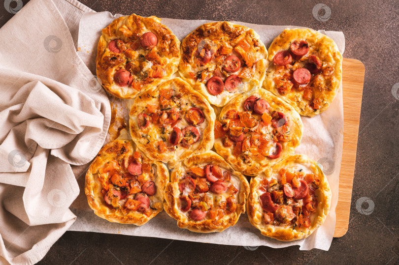 Скачать Свежие пироги для пиццы в горшочках с помидорами, сыром и сосисками на деревянной доске вид сверху фотосток Ozero