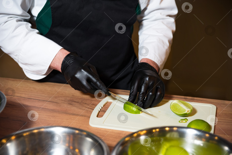 Скачать Профессиональный шеф-повар нарезает лайм на разделочной доске фотосток Ozero