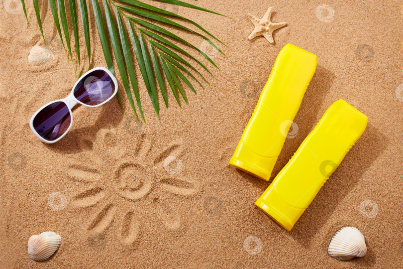Скачать Солнцезащитные кремы, солнцезащитные очки, ракушки и пальмовые листья на песке на пляже. фотосток Ozero