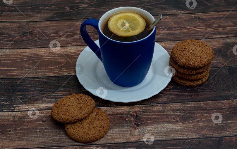 Скачать Овсяное печенье с шоколадной крошкой на белом блюдце. Чашка черного чая на деревянном фоне фотосток Ozero