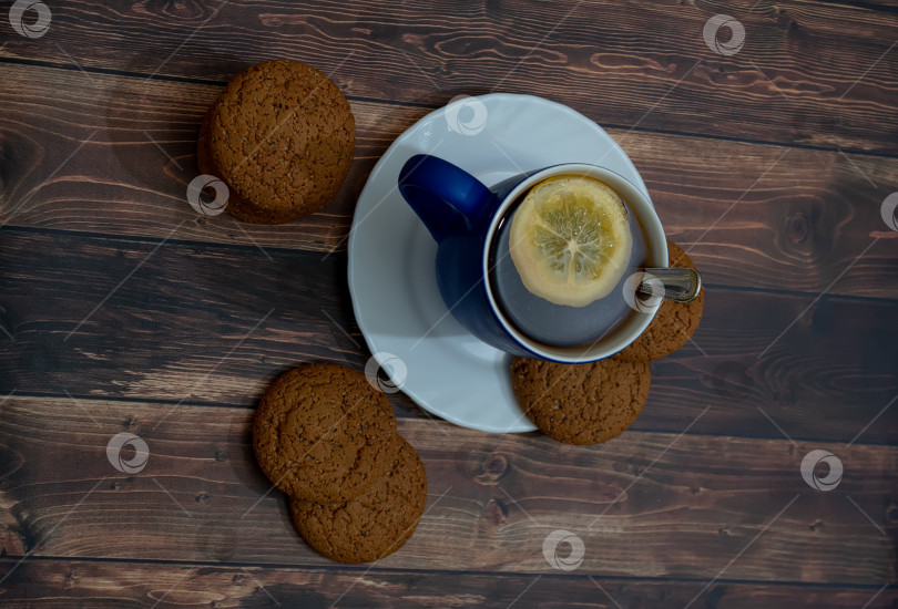 Скачать Овсяное печенье с шоколадной крошкой на белом блюдце. Чашка черного чая на деревянном фоне фотосток Ozero