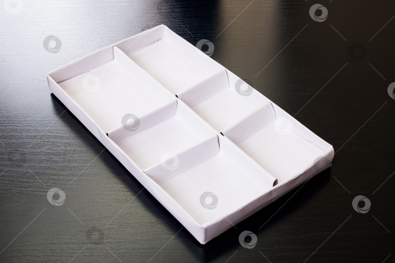 Скачать Белая коробка с ячейками на деревянном столе фотосток Ozero
