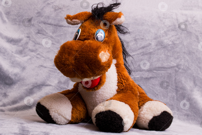 Скачать Мягкая плюшевая игрушечная лошадка на сером фоне фотосток Ozero