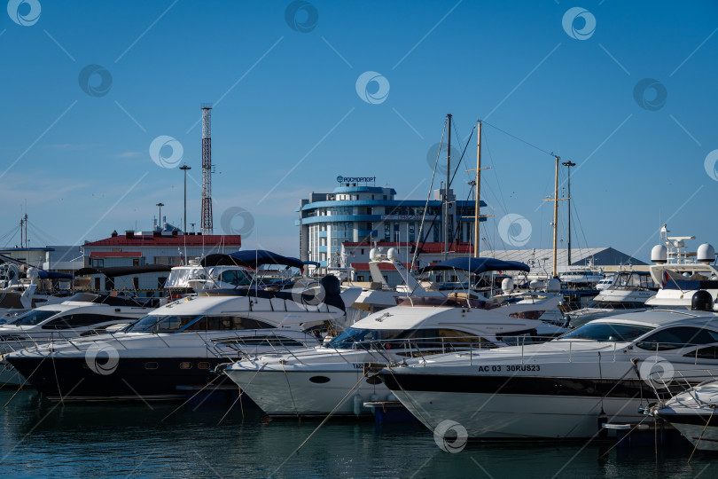 Скачать Яхты и катера у причала Сочинского морского торгового порта. На заднем плане - новое здание Росморпорта. Центр города-курорта. Ясный солнечный зимний день. фотосток Ozero