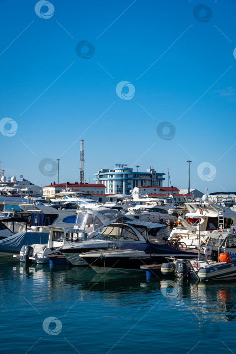 Скачать Яхты и катера у причала Сочинского морского торгового порта. На заднем плане - новое здание Росморпорта. Центр курортного города. Ясный солнечный зимний день. фотосток Ozero