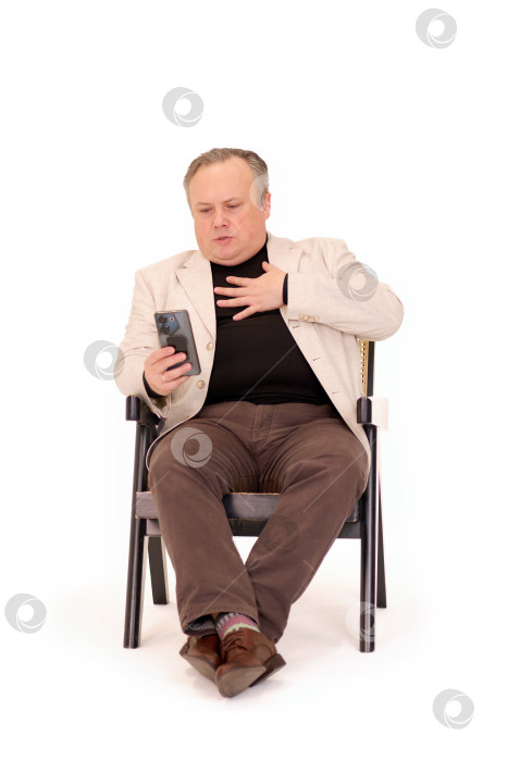 Скачать мужчина в кресле испытывает эмоции, наблюдая за чем-то на своем телефоне на белом фоне фотосток Ozero