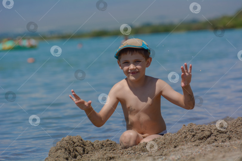 Скачать мальчик играет в песке на пляже у озера фотосток Ozero