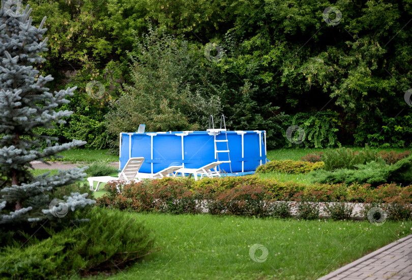 Скачать Голубой переносной загородный бассейн на лужайке загородного сада. Занятия плаванием на заднем дворе загородного дома. Лето, отдых. фотосток Ozero