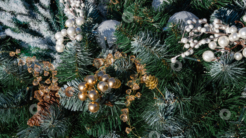 Скачать Большие белые и маленькие золотые шары на зеленых искусственных ветках рождественской елки. Золотые шишки и искусственный снег. Крупный план. Красивые елочные игрушки. Волшебная тема для Нового года и Рождества. фотосток Ozero