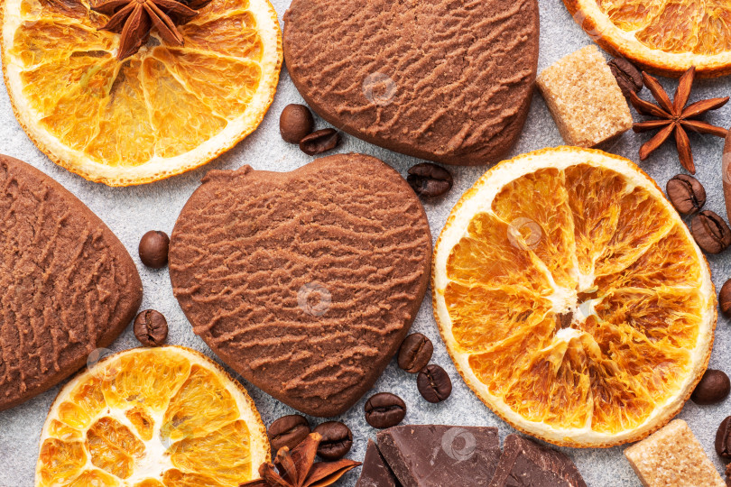 Скачать Печенье с шоколадными сердечками, апельсинами, корицей и пряными специями на сером столе, вид сверху, крупным планом. фотосток Ozero