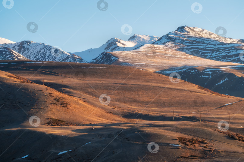 Скачать заснеженный горный хребет, освещенный заходящим солнцем фотосток Ozero