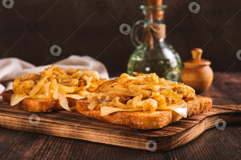 Скачать Аппетитные тосты с плавленым сыром и карамелизированным луком на доске фотосток Ozero