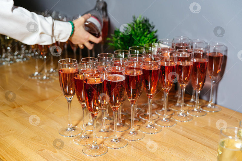 Скачать Разливаем розовое игристое вино по бокалам для торжественного мероприятия фотосток Ozero