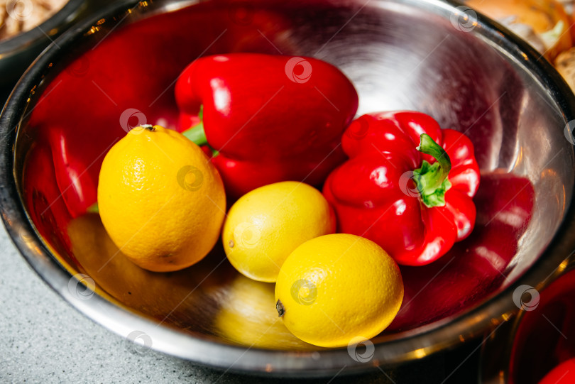 Скачать Свежие лимоны и красный болгарский перец в стальной миске фотосток Ozero