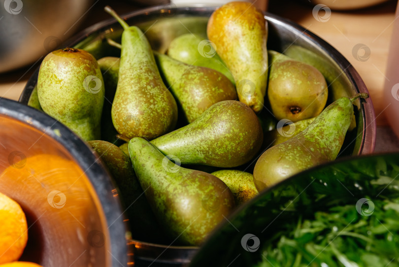 Скачать Миска со свежими зелеными грушами на кухонном столе фотосток Ozero
