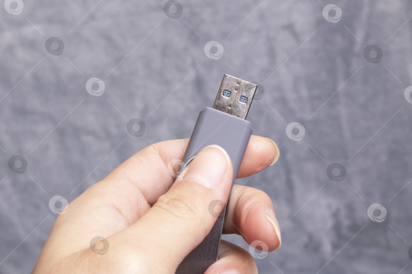 Скачать USB-флешка в руке на сером фоне фотосток Ozero