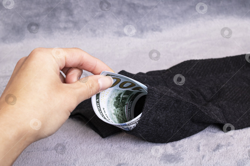 Скачать Доллары в носке и руке на сером фоне фотосток Ozero