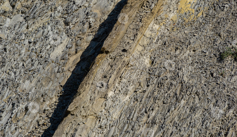 Скачать Полосатая естественная текстура камней и фрагментов горных пород в горах Кавказа на побережье Черного моря в Ольгинке в качестве оригинального текстурного фона. Камень коричневого, желтого, серого цветов. Концепция природы для дизайна фотосток Ozero