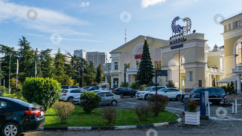 Скачать Сочи, Россия - 23 ноября 2020 года: Площадь с автомобилями перед торговой галереей Grand Marina в морском порту Сочи. Это магазины и бутики, а также круглогодичный выставочный центр. фотосток Ozero