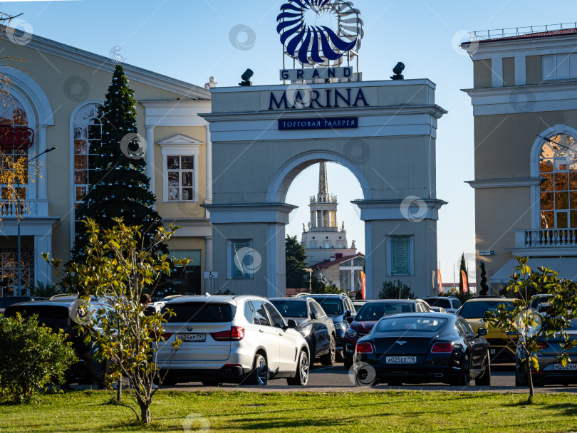 Скачать Торговая галерея Grand Marina в морском порту Сочи со стороны автостоянки. Здание морского порта Сочи в арке торговой галереи. Рождественская елка слева от арки. фотосток Ozero