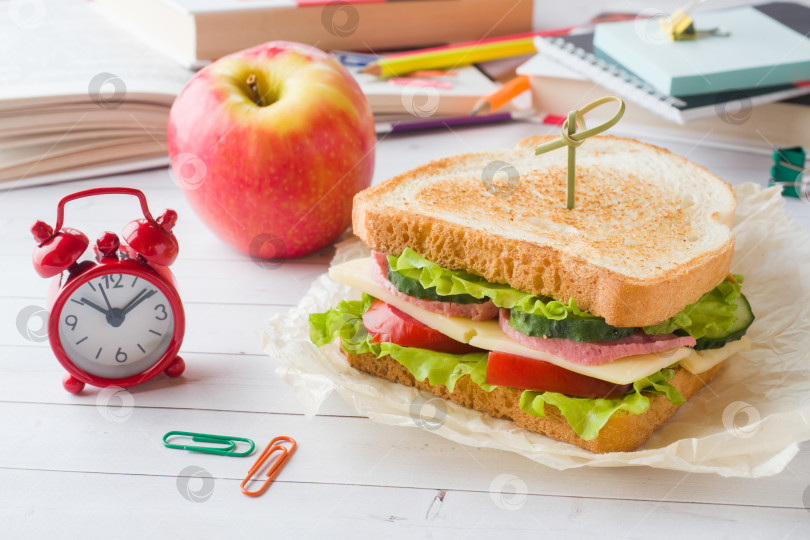 Скачать Перекус в школу с бутербродом, свежим яблоком и апельсиновым соком. Красочные школьные принадлежности. фотосток Ozero