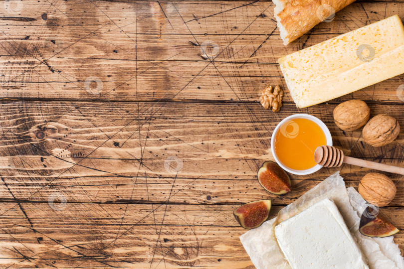 Скачать Закуски с сыром, багетом, медом и орехами на деревянной столешнице в деревенском стиле с местом для копирования. фотосток Ozero