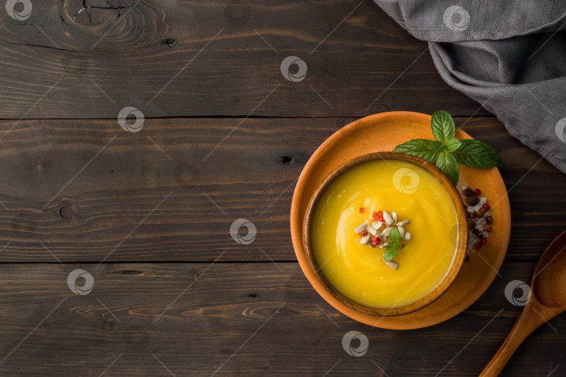 Скачать Тыквенный суп-пюре со специями в деревянных мисках на темных досках. фотосток Ozero