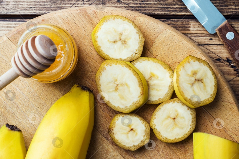 Скачать Банан и нарезанный на кусочки банан с медом на деревянном фоне, крупным планом фотосток Ozero