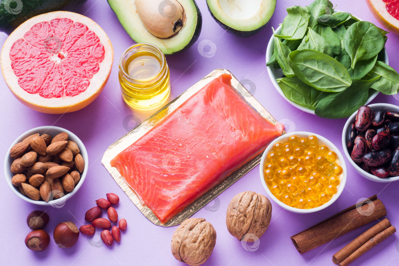 Скачать Концепция здорового питания с антиоксидантными продуктами: рыба и авокадо, орехи и рыбий жир, грейпфрут на розовом фоне. фотосток Ozero