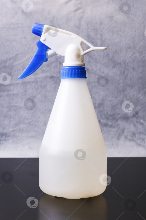 Скачать Белая бутылка для полива растений на столе фотосток Ozero