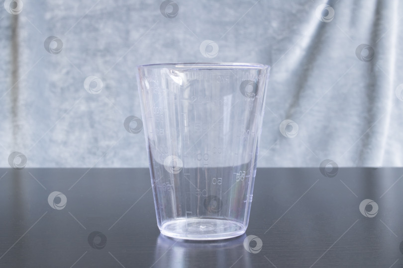 Скачать Пластиковый мерный стаканчик на сером фоне фотосток Ozero