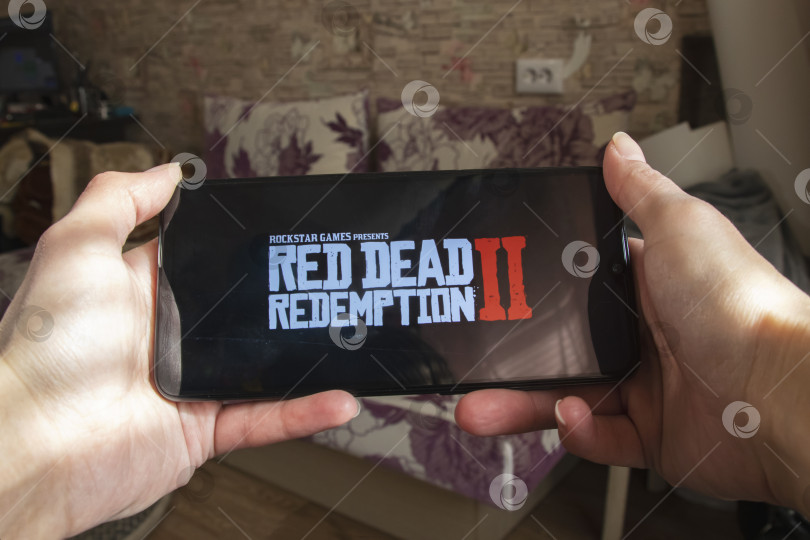 Скачать БЕЛАРУСЬ, НОВОПОЛОЦК - 27 марта 2021 года: игра Red dead redemption на дисплее телефона фотосток Ozero