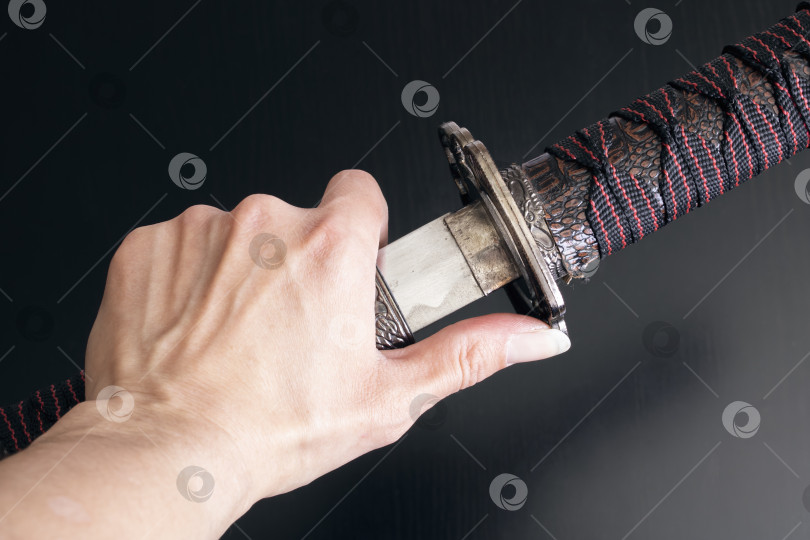 Скачать Самурайский меч и ножны в руке на деревянном фоне фотосток Ozero