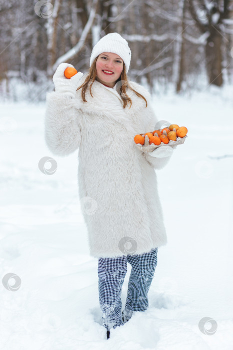 Скачать Оранжевые мандарины лежат в картонной экологически чистой коробке из-под куриных яиц. Женские руки на улице с коробкой мандаринов в руках фотосток Ozero
