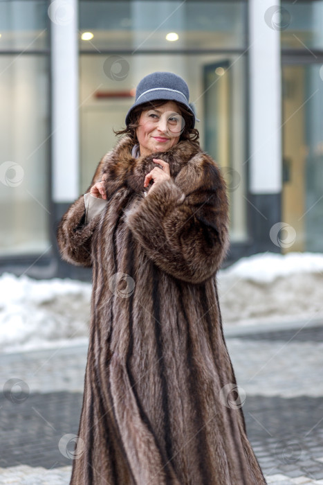 Скачать Стильная женщина средних лет в шубе и шапке на городской улице во время рождественских праздников фотосток Ozero
