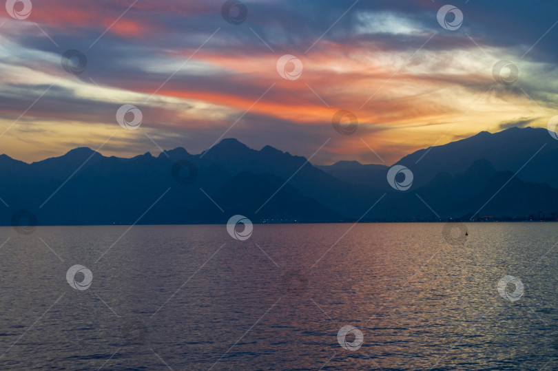 Скачать Яркое красочное небо на закате над морем и горами. фотосток Ozero
